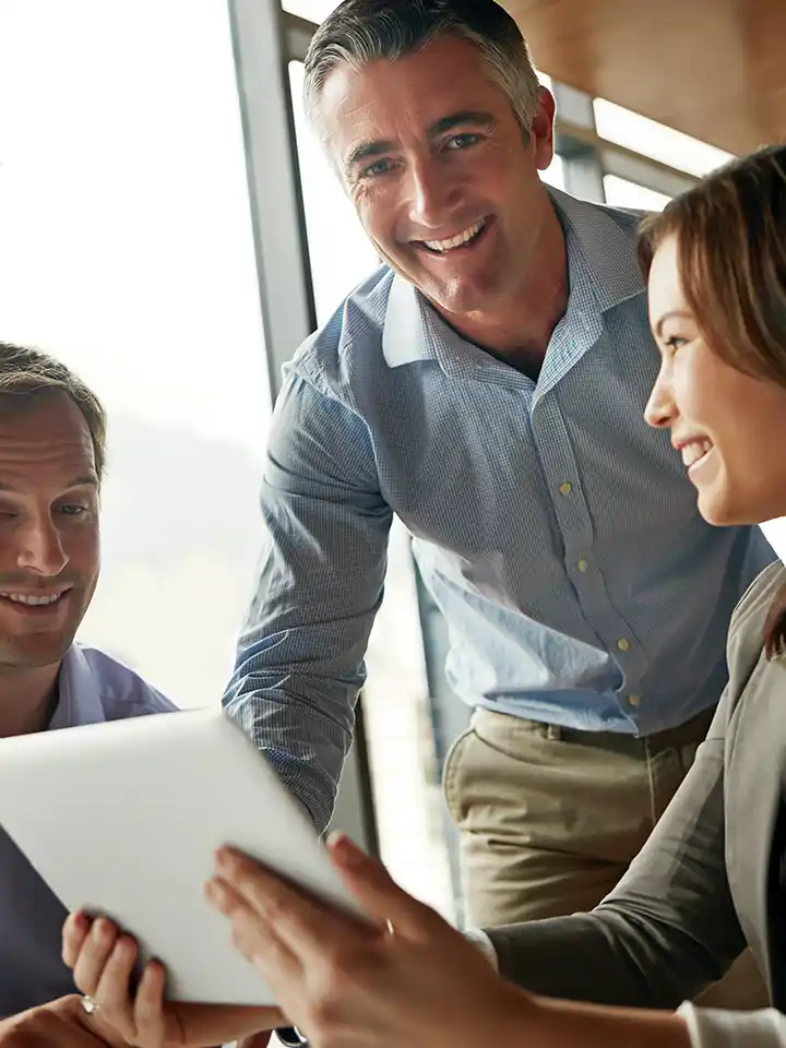 Three corporate people looking at a tablet